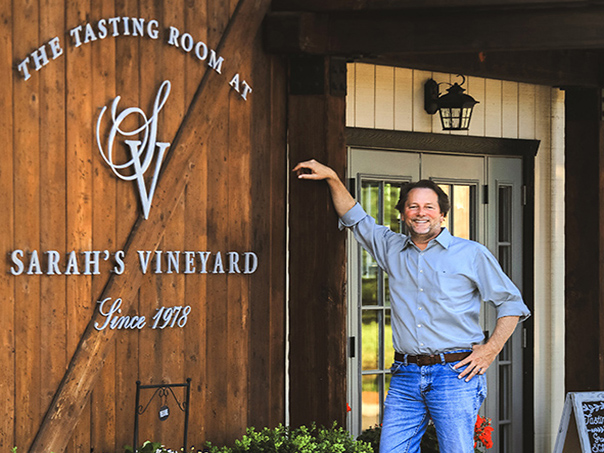 Tim Slater standing out side tasting room in front of Sarah's Vineyard sign.