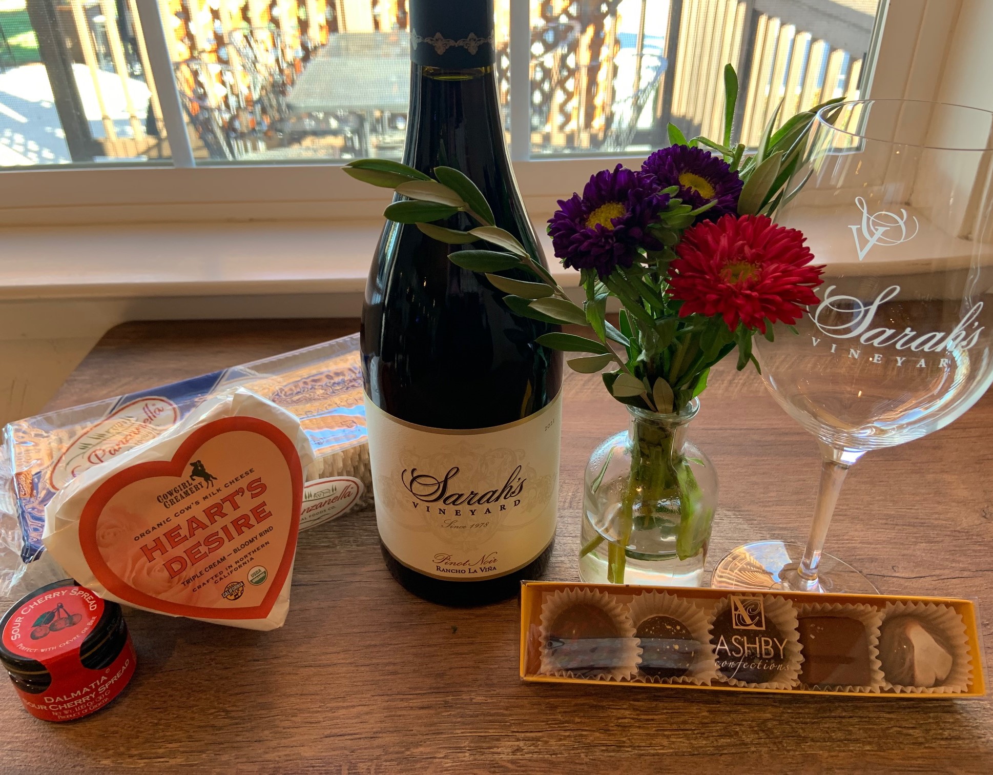 bottle of wine with cheese, crackers, chocolates and a glass